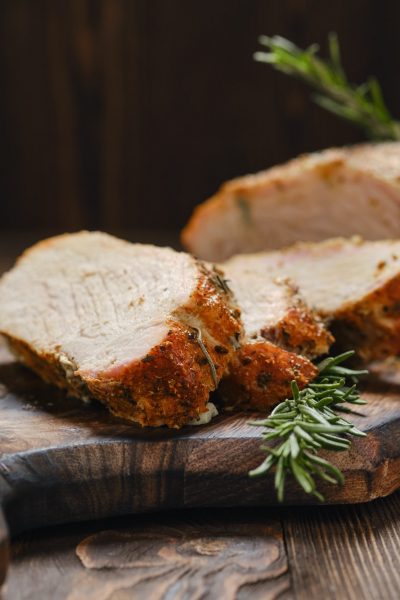 Closeup view of pork collar joint baked in oven on wooden serving board